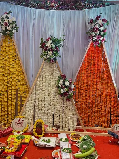 Another view of the modern A-frame pooja setup, showing the beautiful combination of yellow, white, and orange flowers.