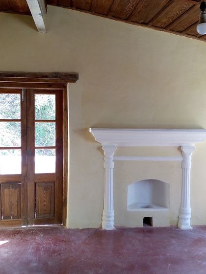 The same room after restoration, with a repaired fireplace, clean walls, and restored wooden door, now ready for a new lease of life.