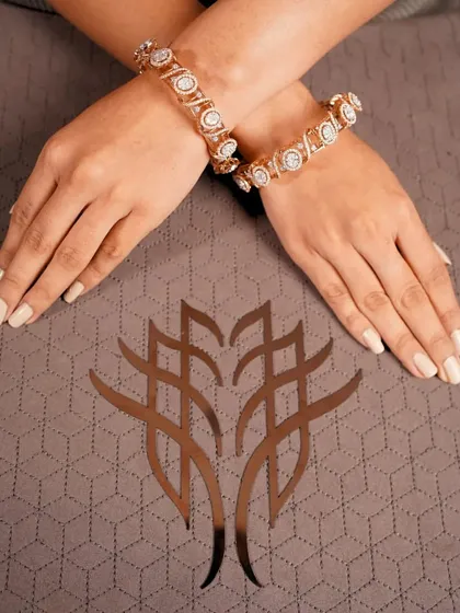A pair of magnificent diamond bangles, worn crossed on the wrist, showcasing their substantial brilliance.
