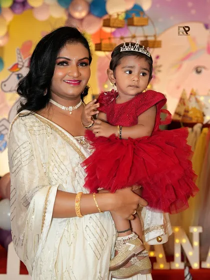 Capturing the magic of a first birthday party. This event photo shows a mother holding her little princess, both looking radiant amidst the festive unicorn-themed decorations.