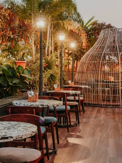 Ambiance is everything in hospitality. At this resto-bar's outdoor terrace, I used sculptural rattan pods and warm street-style lamps to create private, magical seating areas surrounded by lush greenery, perfect for an evening escape.