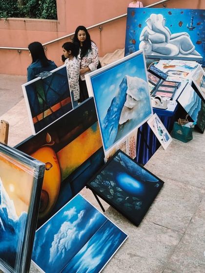 Snippets from our 'Sublime Fiesta' event, showing an outdoor display of various artworks, including landscapes and spiritual paintings.