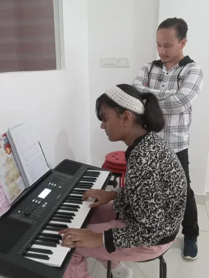 An instructor observing his student's keyboard practice, ensuring she develops the correct posture and technique.