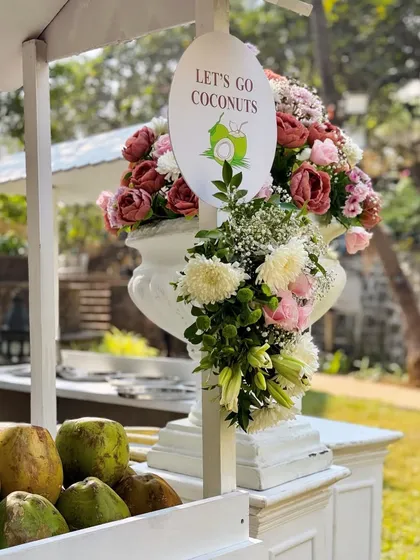 A close up of my 'Let's Go Coconuts' cart. The cart is beautifully decorated with flowers, adding an elegant and tropical touch to the beverage station.