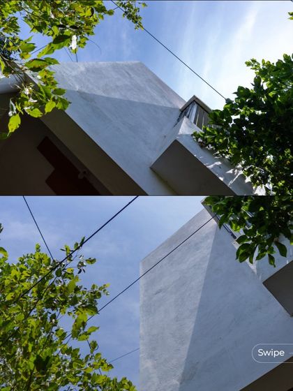 A low-angle shot of the Gifty Residence, emphasizing its clean geometric forms against the sky, framed by the surrounding greenery.