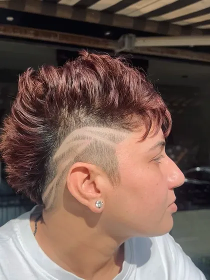 Hair is a canvas for art. This edgy mohawk style is combined with a custom hair tattoo, a design shaved into the side for a truly unique and bold statement. This is for clients who want to push boundaries and wear their personality.