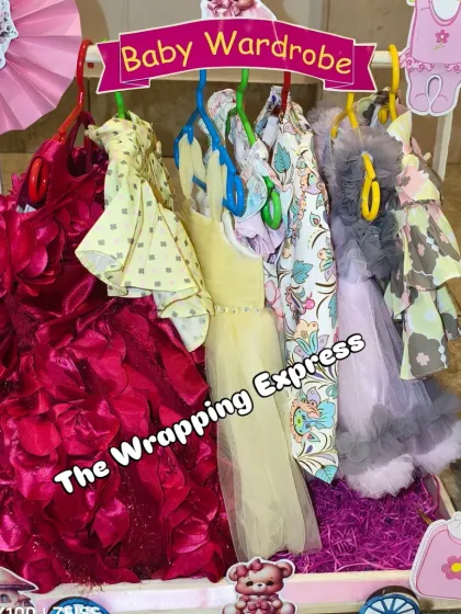 A beautiful wardrobe display for a baby girl, featuring a stunning red party dress with rose petal details.