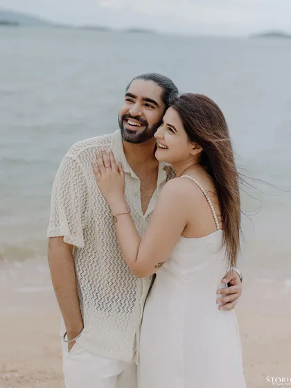 A joyful, windswept portrait of the couple on the beach.