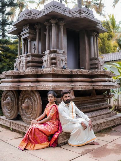 A relaxed portrait of a couple sitting by our Hampi stone chariot replica.