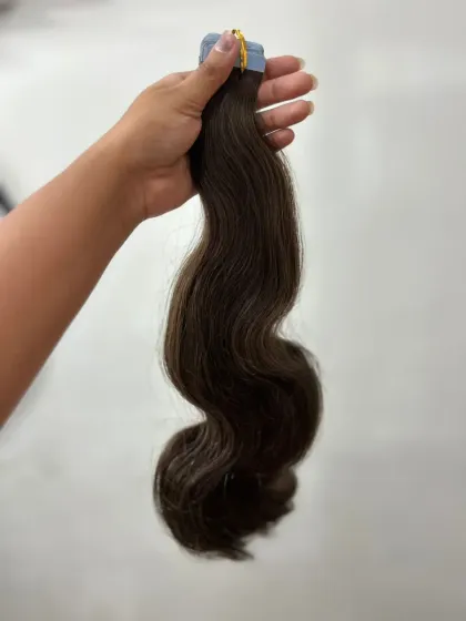 Here I am holding a thick weft of wavy tape-in extensions, showing the rich color and healthy sheen of the hair. This is a great option for adding both volume and a soft wave.