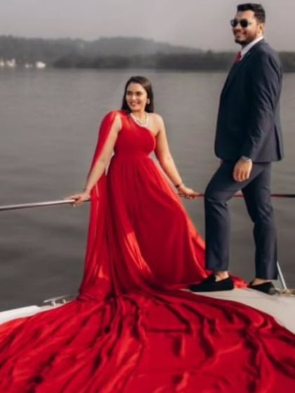 A perfect pose on a yacht, showing our one-shoulder red trail gown. This rental is a client favorite for its simple elegance and dramatic, flowing trail that catches the sea breeze beautifully.