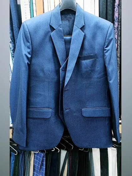A finished blue three piece suit hanging in my shop, ready for the client. Notice the clean stitching and the perfect shape of the lapels, a sign of quality craftsmanship.