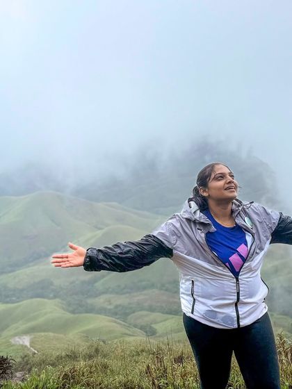 Feeling on top of the world. A trekker spreads her arms wide to embrace the misty views at Kudremukha.
