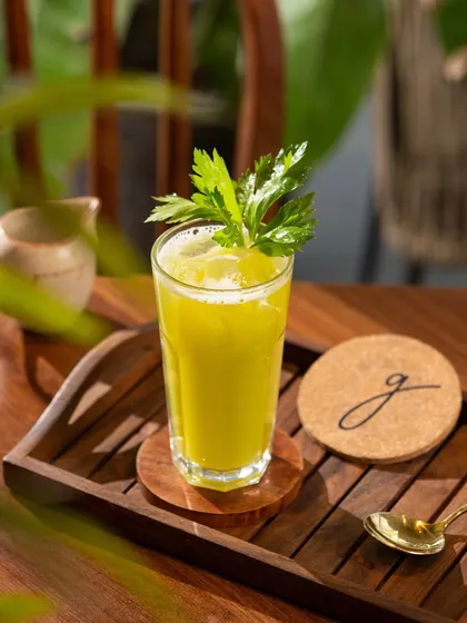 A healthy green juice garnished with celery. The focus is on the vibrant green color, signaling health and wellness.