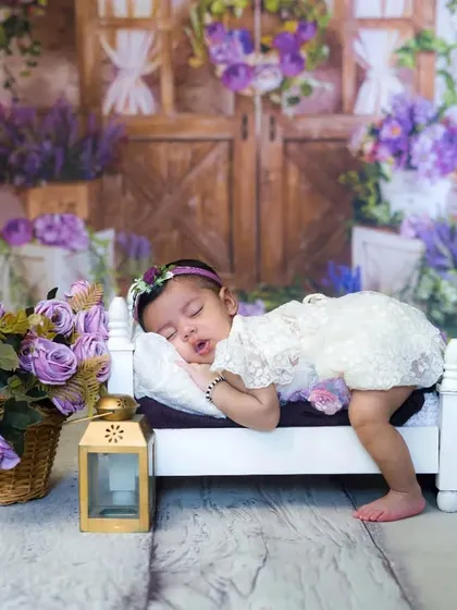 A wide shot of a newborn girl sleeping peacefully in a lavender-themed setup. The details and props come together to create a stunning, artistic image.