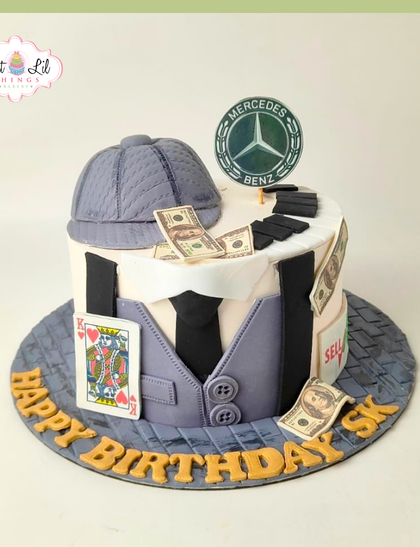 A high-roller's birthday cake, featuring a Peaky Blinders-style cap, playing cards, money, and a Mercedes-Benz logo.