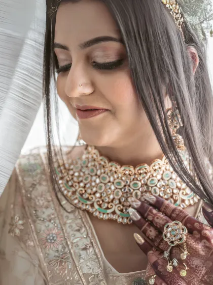 A serene close-up of a bride with her eyes closed, showcasing her intricate jewelry and flawless makeup. This shot emphasizes the beauty and artistry of the bridal look.