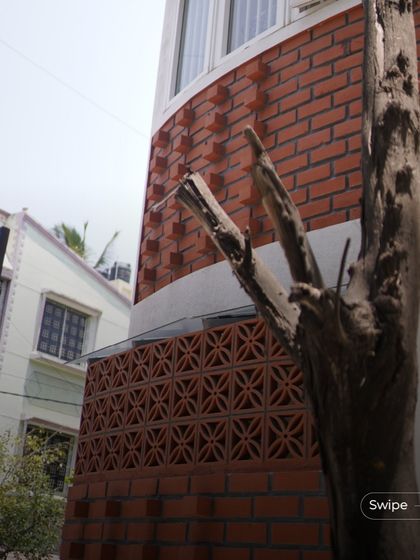 The exterior of the Gopal Residence features a curved corner with intricate terracotta jali work and projecting brick patterns, adding texture and character to the facade.