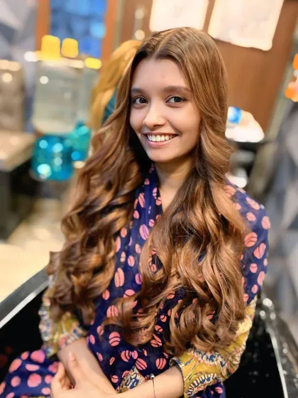The client is all smiles with her new hair colour. The warm tones complement her skin tone perfectly and give her hair a rich, vibrant look.