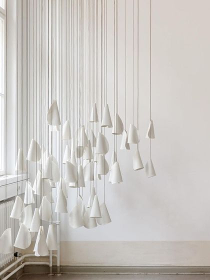 A large, dense cluster of Bocci 21 pendants installed in a bright, white room, creating a stunning contrast and a powerful sculptural statement.