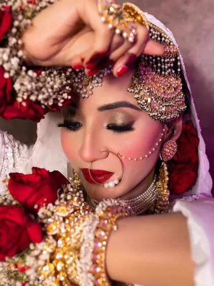 A close-up of this bride's artistic makeup. The combination of red roses, a classic nath, and perfectly blended eyeshadow creates a look that is both traditional and high fashion.