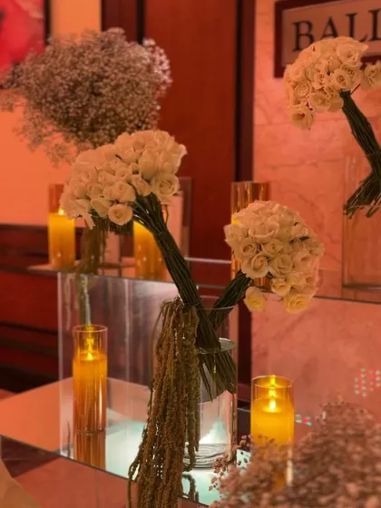 Bouquets of white roses and candles on mirrored surfaces create a classic and sophisticated decor element.