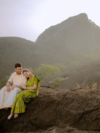 A serene wide shot of the couple enjoying the vast, misty mountain view together.