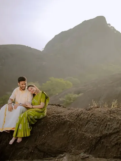 A serene wide shot of the couple enjoying the vast, misty mountain view together.