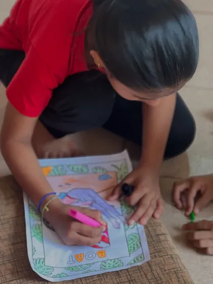 A young girl carefully colors a drawing of Boat Pose. This activity helps reinforce the names and shapes of the asanas in a fun, memorable way.