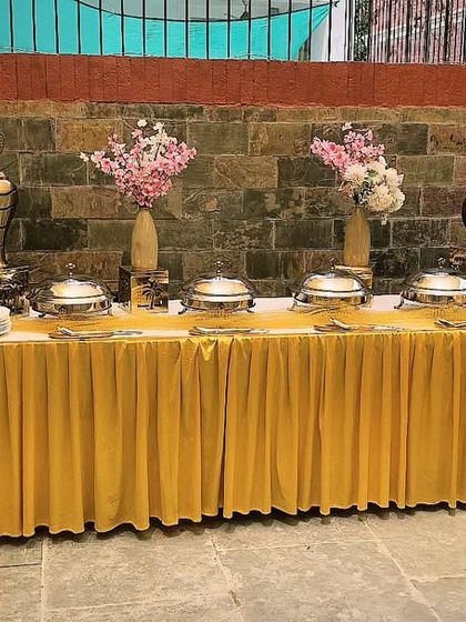 A bright and cheerful buffet setup with a golden theme for 45 guests. The floral vases and elegant chafing dishes add a touch of class to this outdoor event.