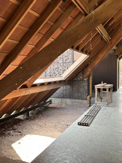 Light is sculpted and guided through the Alibaug residence. A carefully placed skylight in the wooden roof washes the stone wall with natural light, highlighting the texture of the materials and animating the corridor.