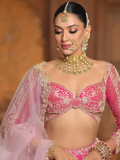 A poised and elegant shot focusing on the upper body. The sleek hair at the crown, combined with the start of the floral braid, complements the intricate jewellery and outfit.