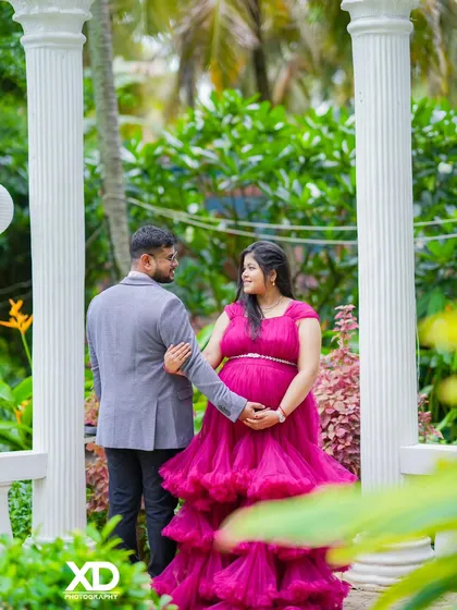 A romantic shot from behind, showing the couple walking hand-in-hand through a garden.