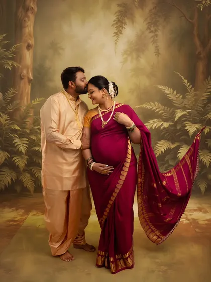 A tender forehead kiss in a forest setting. This Ravi Varma-style portrait captures the protective and loving embrace of the father-to-be, wrapped in traditional attire.