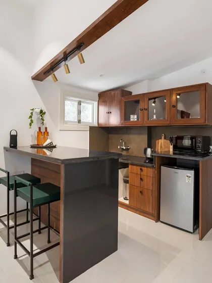 A compact and functional kitchenette or bar area, complete with a mini-fridge, sink, and storage. The dark stone countertop and wooden cabinetry create a sleek and modern look.