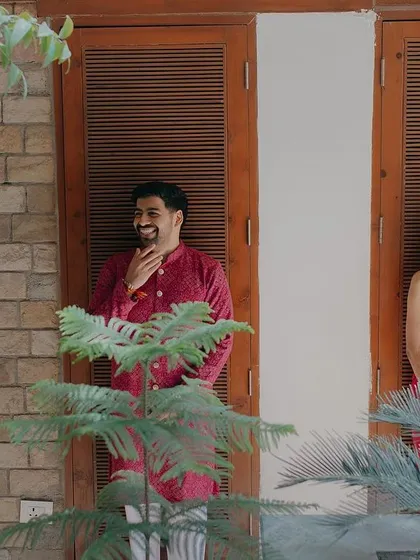 A candid moment of shared laughter. This shot, framed by lush greenery, captures the couple in separate windows, creating a playful and unique composition that feels natural and unposed.
