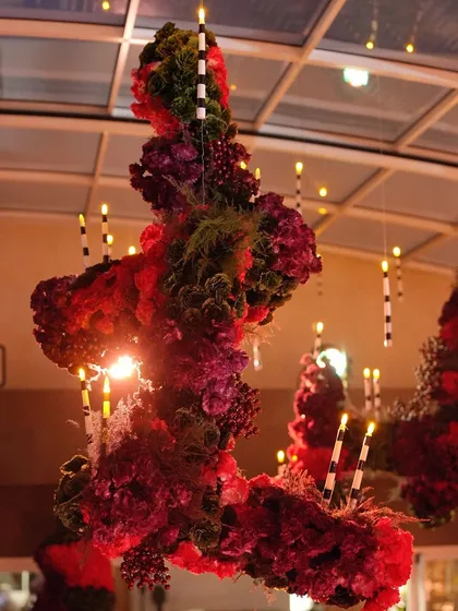 A stunning floral chandelier with hanging candles, creating a dramatic focal point in the red-themed space.