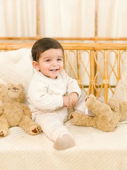 The purest joy captured in a sitter session. The baby's giggling expression and playful pose make this an incredibly cheerful and charming photograph.
