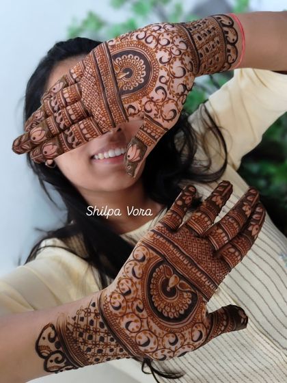 A happy client showing off her intricate paisley and peacock design.