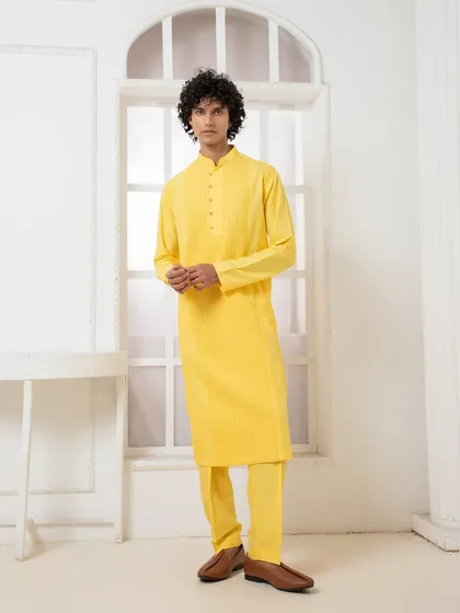 A vibrant yellow kurta set designed for daytime festivities. The simple silhouette is elevated by the textured fabric and meticulous pintuck detailing on the chest.