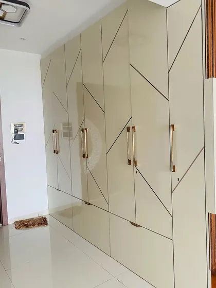 A full-height wardrobe with a striking geometric pattern on high-gloss laminate, paired with elegant gold handles.