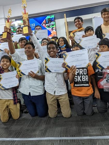 Champions of the day! Students proudly hold up their certificates and trophies after a community robotics competition. We believe in recognizing and celebrating every student's hard work.