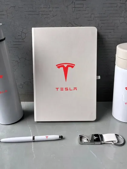 Here are the items from the white Tesla gift set, displayed to show the quality of each piece. The set includes a temperature flask, a travel mug with a spill-proof lid, a diary, a pen, and a keychain.