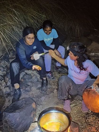 Campers with headlamps cook their dinner over a fire, an authentic wilderness camping experience.