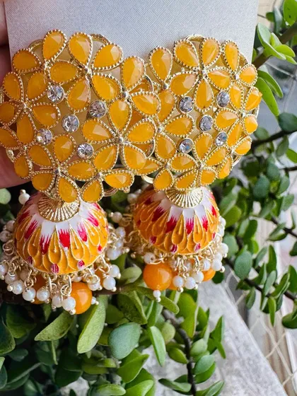 Bright and sunny, these yellow meenakari jhumkas are perfect for haldi or mehendi functions. The enamel work is detailed with hints of red and white, adding a unique touch.