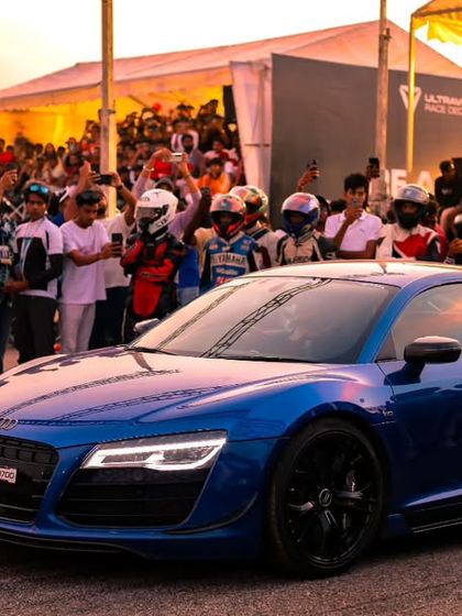 A stunning blue Audi R8, a supercar icon, surrounded by an adoring crowd at sunset. These are the moments that define the Vroom festival experience.