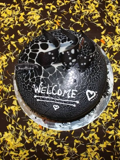 A top-down view of a 'Welcome' cake placed on a bed of yellow flower petals. This is a small but thoughtful detail that can be part of a larger welcome home decoration package.