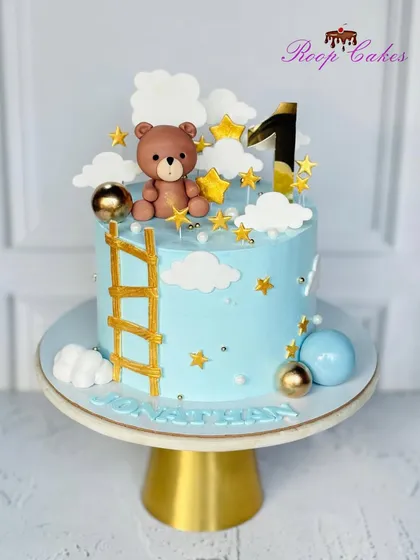 One year of sweet moments and endless joy. This first birthday cake features a teddy bear climbing a golden ladder to the stars.