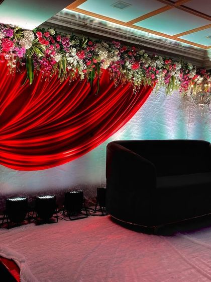 A classic stage design for a reception or sangeet. I used rich red fabric draping combined with a thick border of colorful flowers like roses, lilies, and carnations.