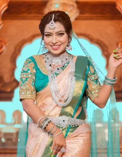 A model in a beautiful teal and cream saree, wearing a layered American diamond set with green stone accents.